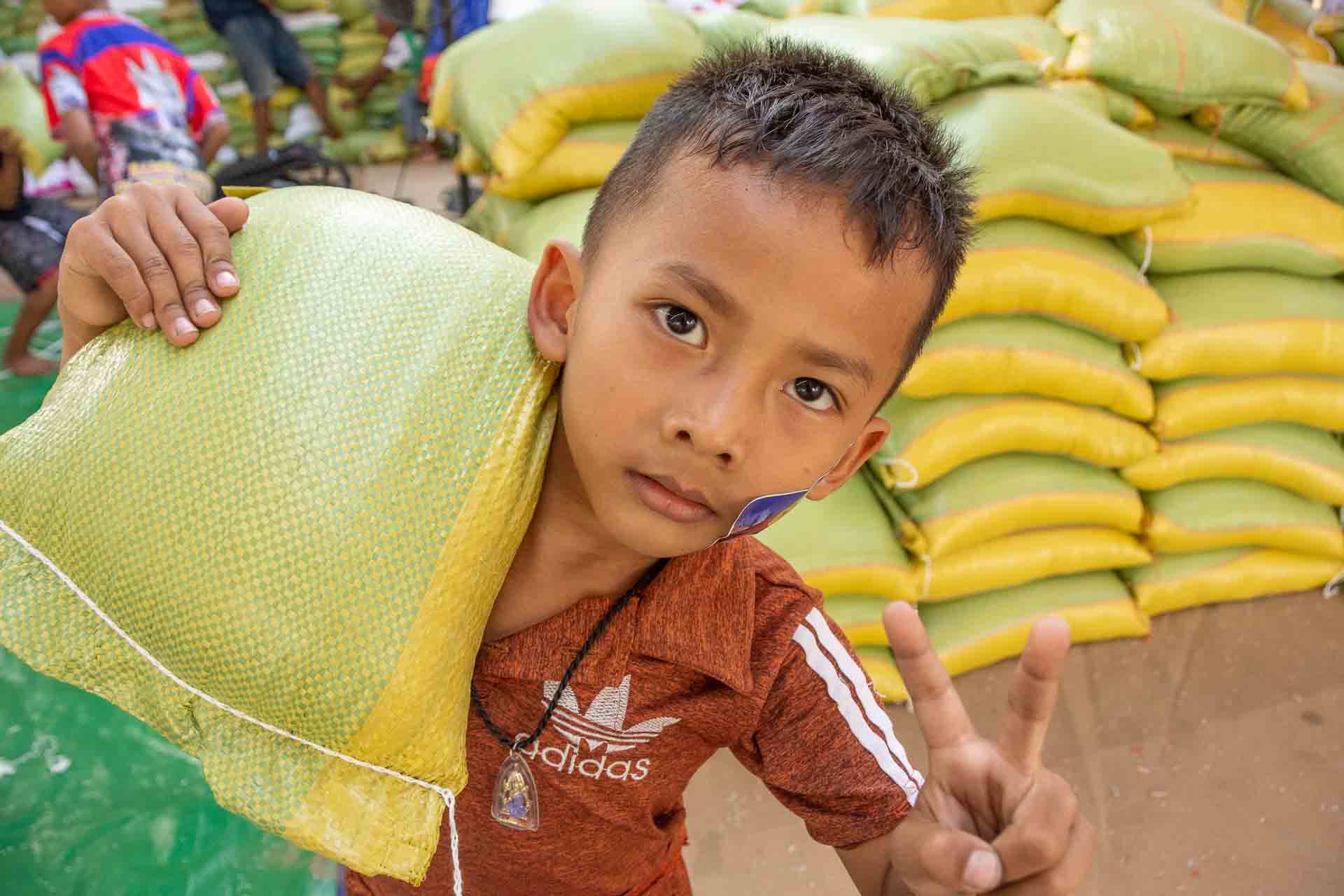 A boy carrying a rice sack makes a peace sign at a donation centre in Beung Kok, Phnom Penh, Cambodia.